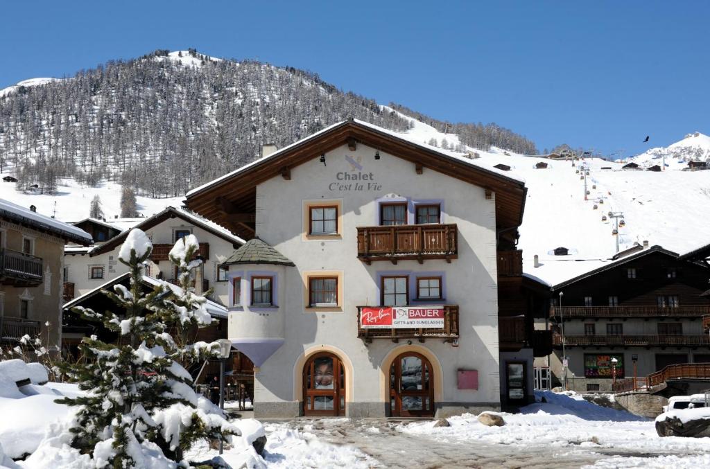 um grande edifício na neve em frente a uma montanha em Chalet C'Est La Vie em Livigno
