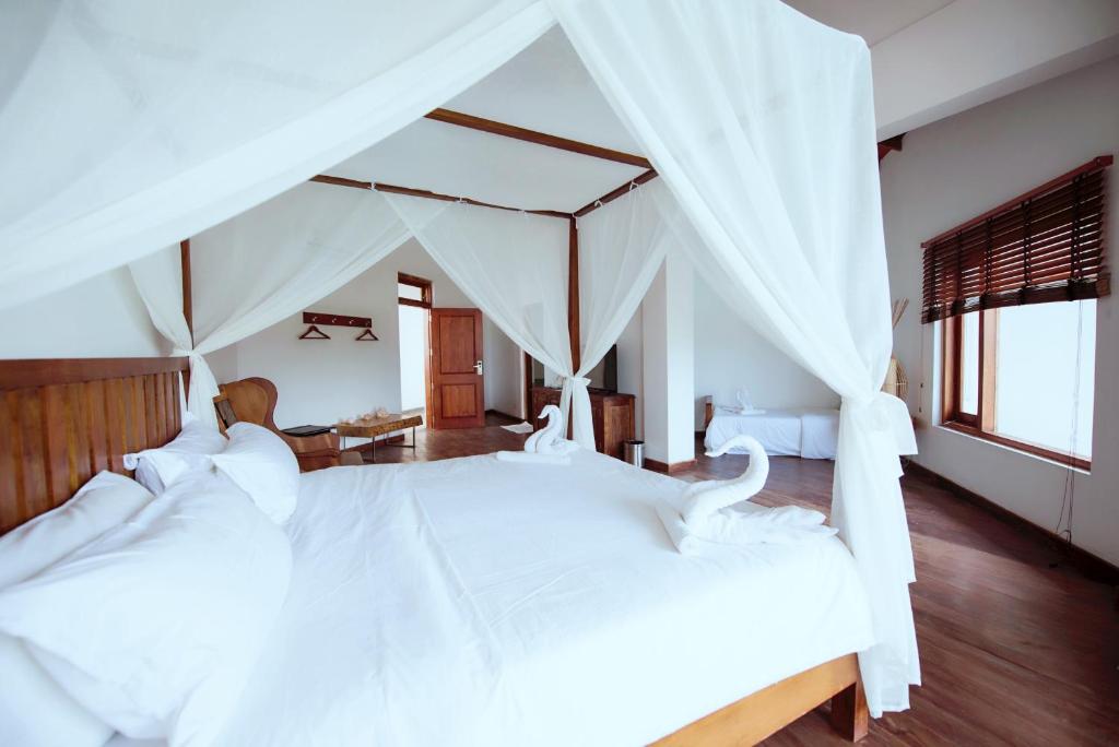 a bedroom with a large white bed with a canopy at Cardamon Hotel Nilaveli in Nilaveli