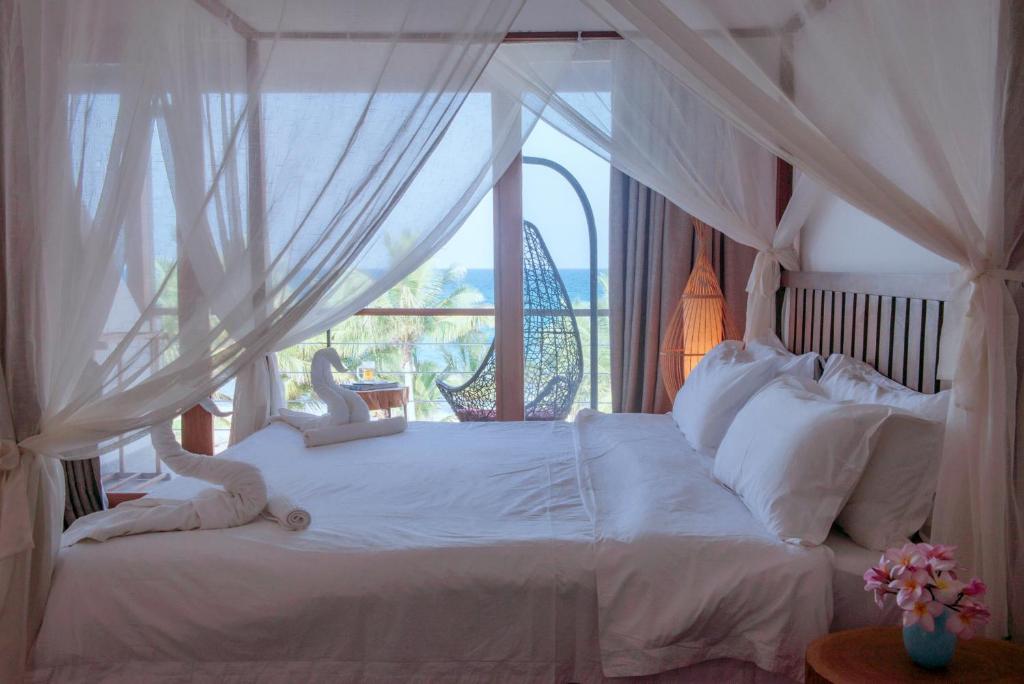 a bedroom with a white bed with a window at Cardamon Hotel Nilaveli in Nilaveli