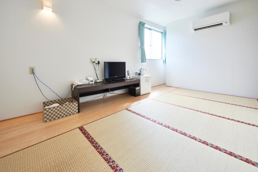 a living room with a television and a rug at Hotel Select Inn Saitama Moroyama in Ogose