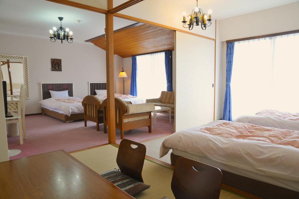 a hotel room with two beds and a desk and a table at Tateyama Resort Hotel in Tateyama