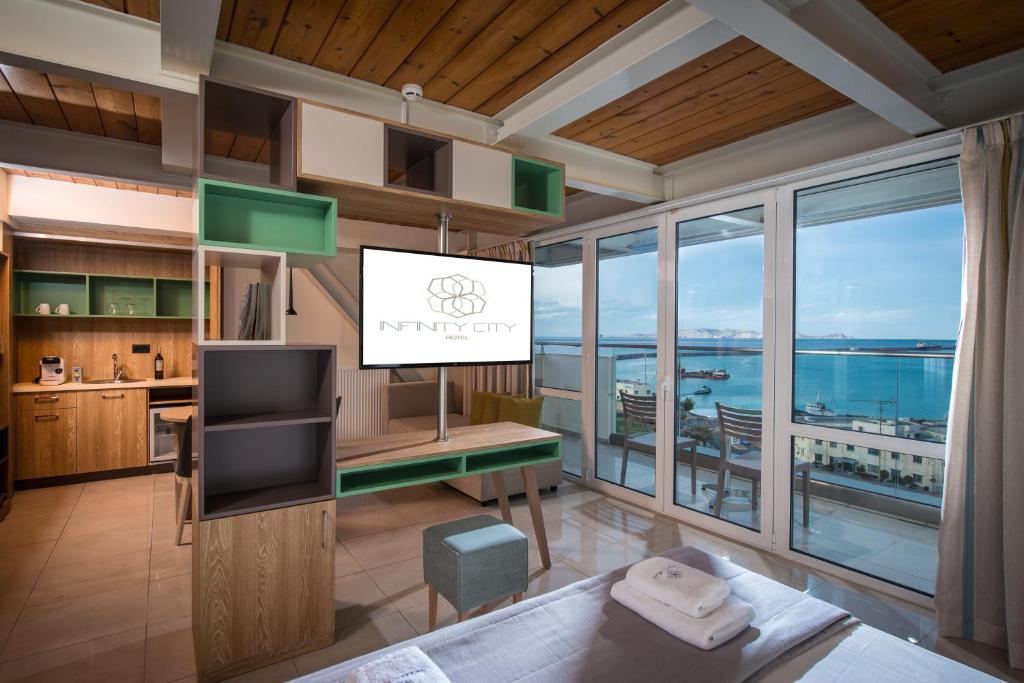 a living room with a television and a view of the ocean at Infinity City Boutique Hotel in Heraklio Town