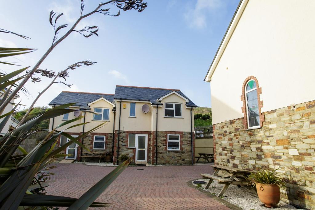 una casa con un patio de ladrillo junto a una iglesia en Tregurrian Villas, en Newquay