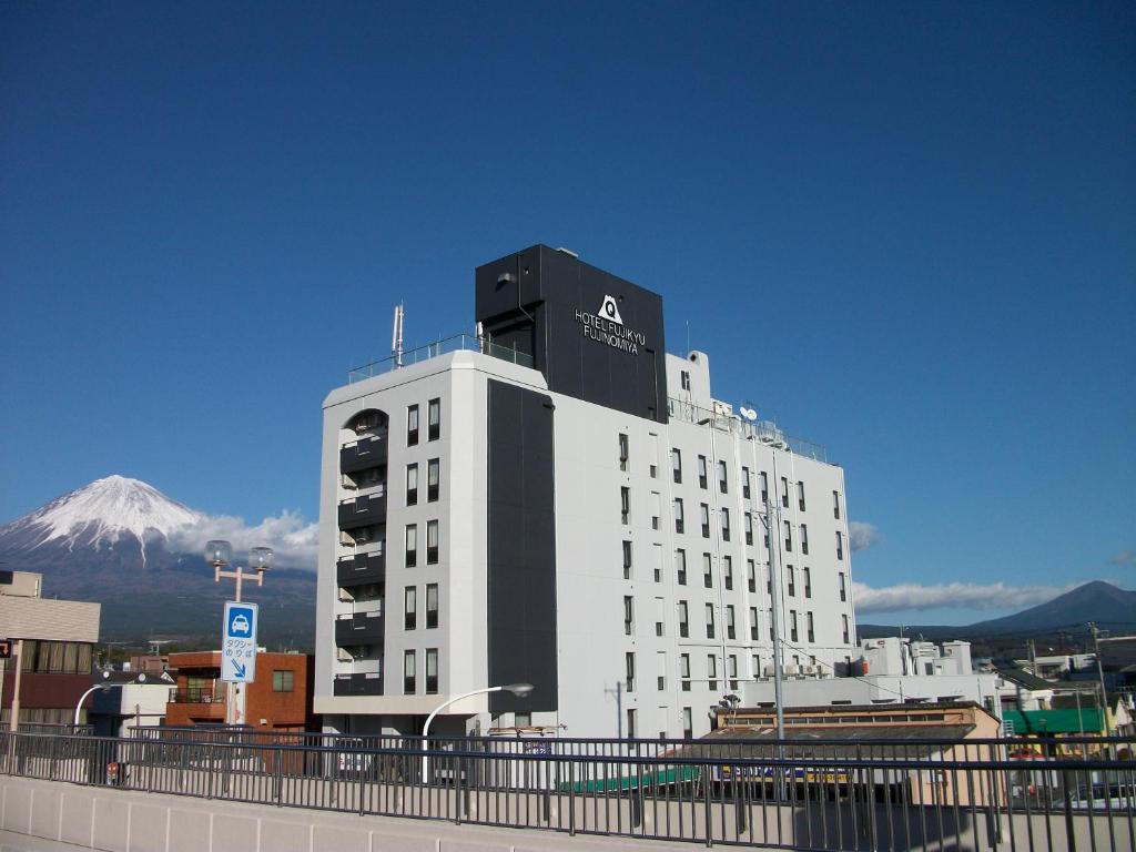 a large white building with a mountain in the background at Fujinomiya Fujikyu Hotel in Fujinomiya