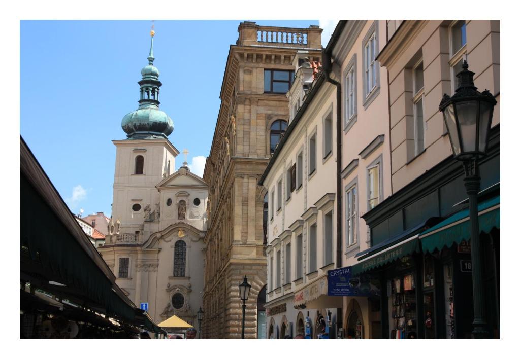 una calle de la ciudad con edificios y una torre del reloj en Prague Golden Age, en Praga