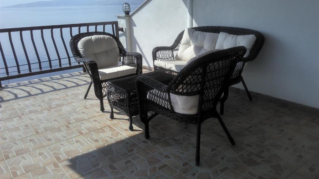 three wicker chairs sitting on a balcony at Delfin Apartments in Sveti Juraj