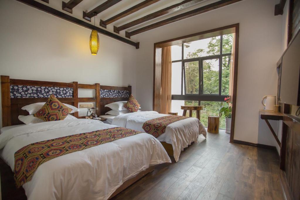 a bedroom with two beds and a window at 张家界畔山驿栈 in Zhangjiajie