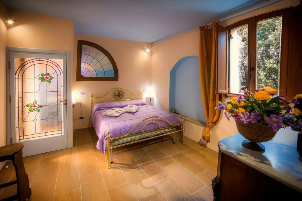 ein Schlafzimmer mit einem Bett und Fenstern sowie einer Vase aus Blumen in der Unterkunft Agriturismo La Torre Di Monsindoli in Siena