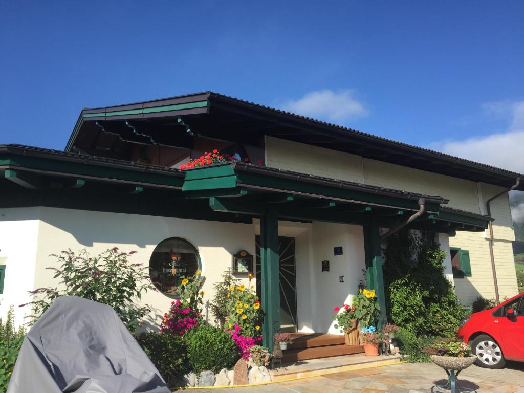 a house with a balcony and flowers on it at Pension Wieser "Baschtlmai" in Altenmarkt im Pongau