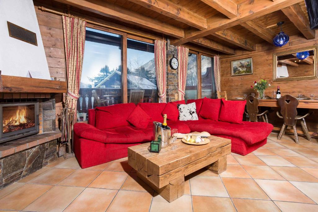 - un salon avec un canapé rouge et une cheminée dans l'établissement Parc du Mont Blanc 12 appt - Chamonix All Year, à Chamonix-Mont-Blanc