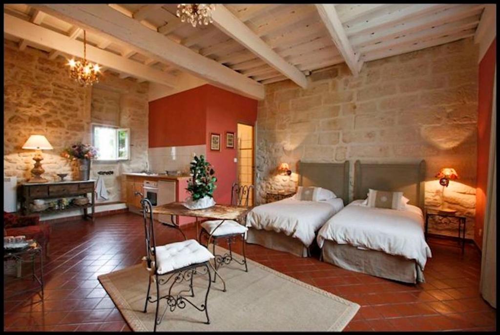 a bedroom with two beds and a table and a kitchen at Le trente trois in Uzès
