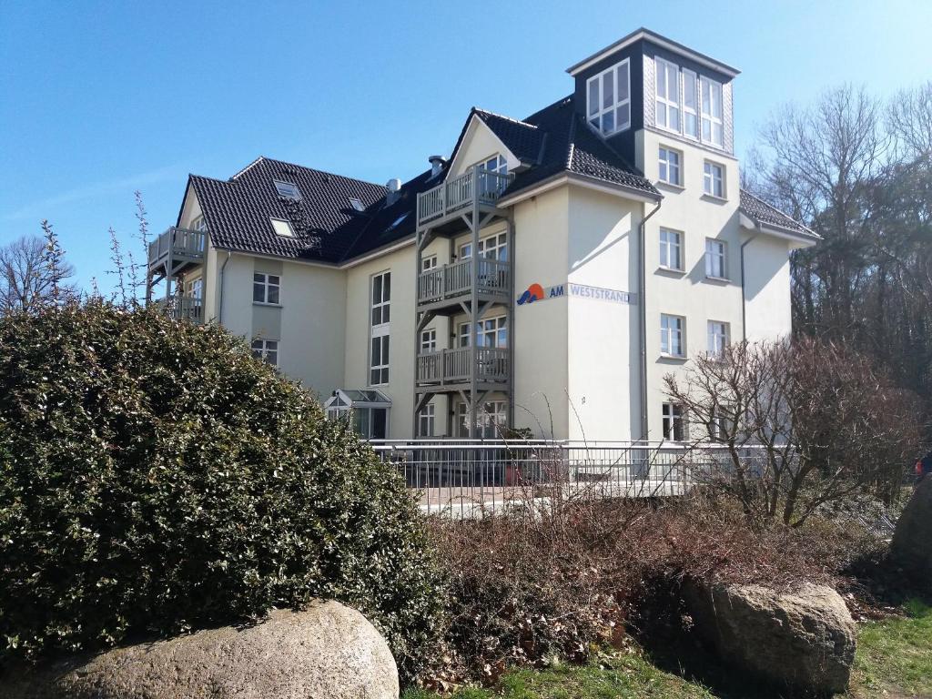a large white building with a black roof at Am Weststrand Apartmenthaus Waldeck in Kühlungsborn