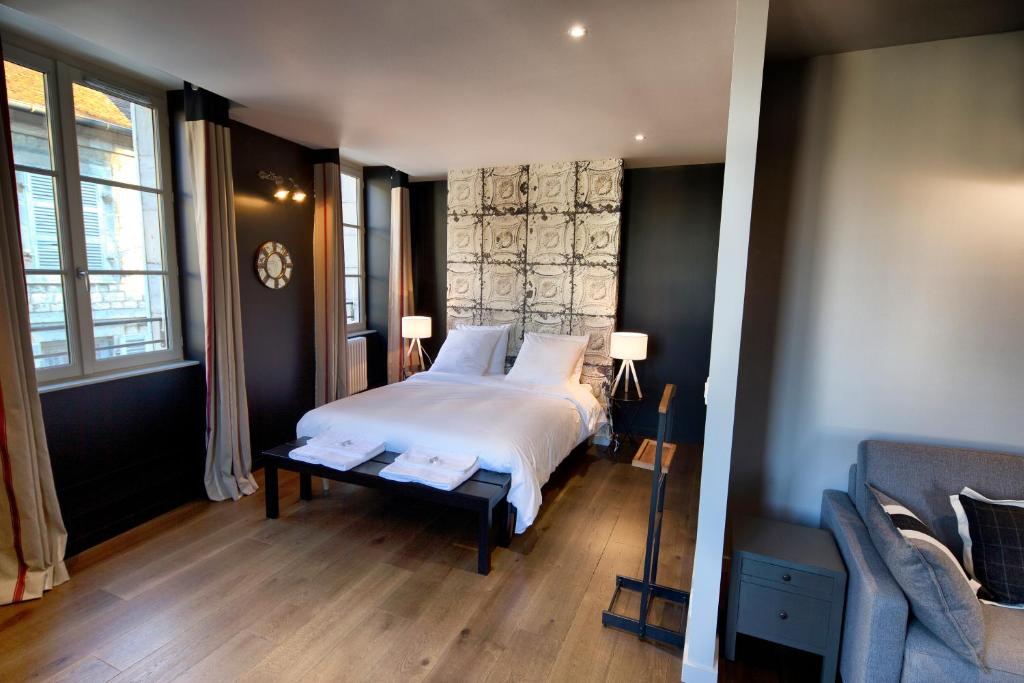 a bedroom with a bed and two windows and a couch at Le Comptoir du Voyageur in Arbois