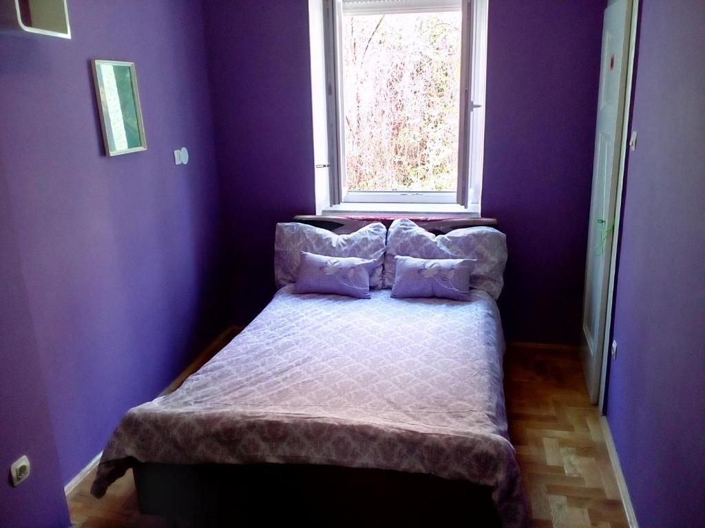 una camera da letto con un letto con pareti viola e una finestra di Apartment Garson a Zagabria