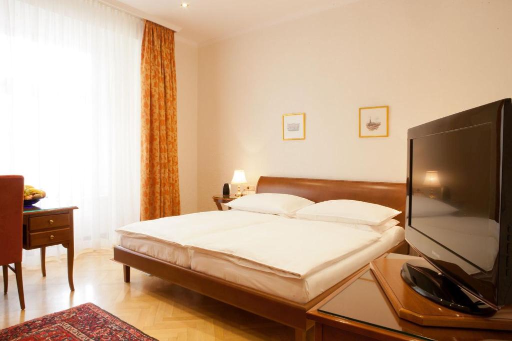 a hotel room with a bed, television and a desk at Hotel Kaiserin Elisabeth in Vienna