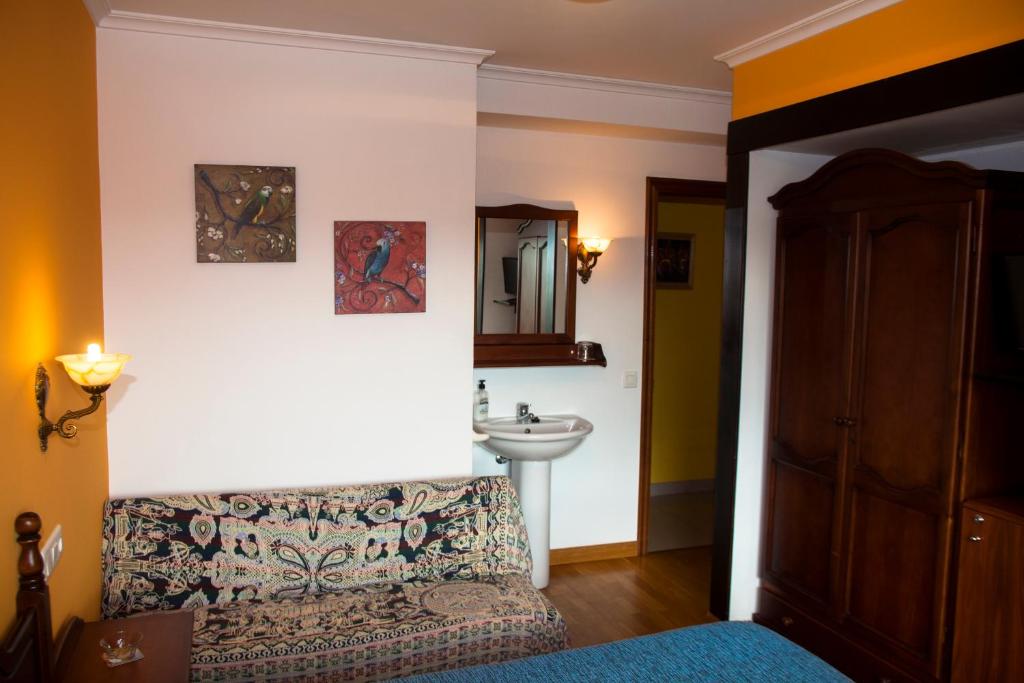 Habitación con cama, lavabo y espejo. en Hospedaxe Carragal, en Ribadeo