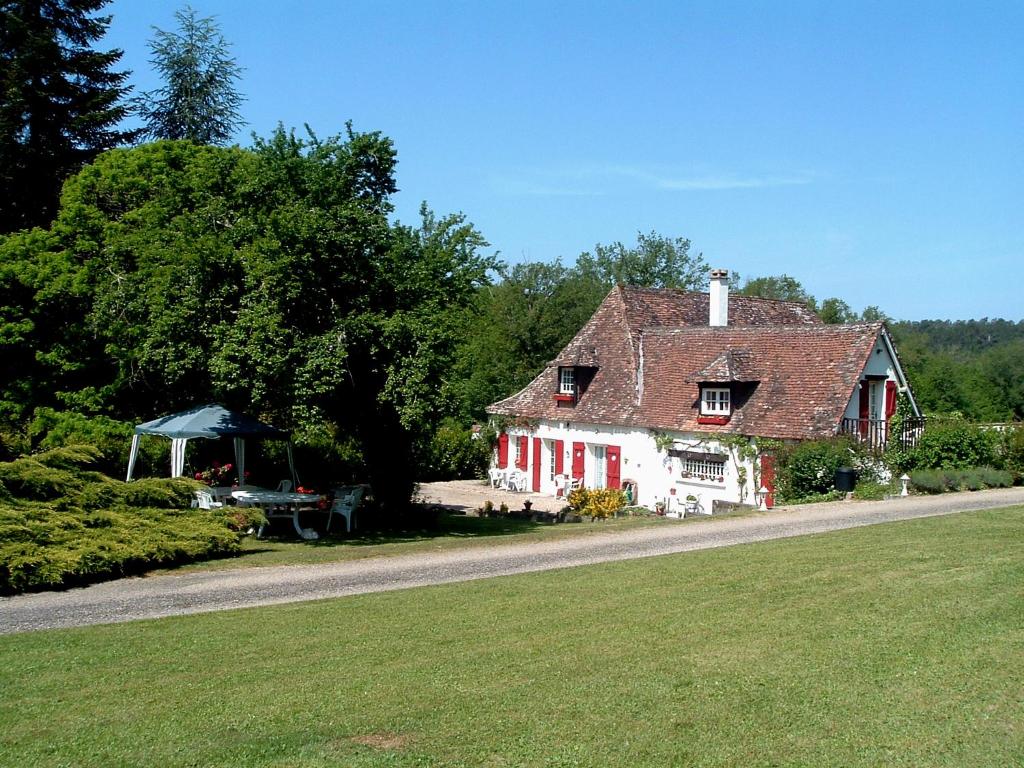 a small white house with red shutters on a road at Le Clos des Archers in Laveyssière