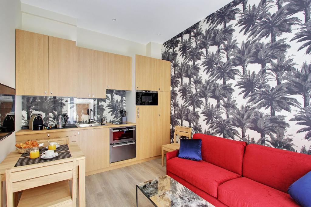 a living room with a red couch and a kitchen at Milestay Opera Lafayette - Serviced Apartment in Paris