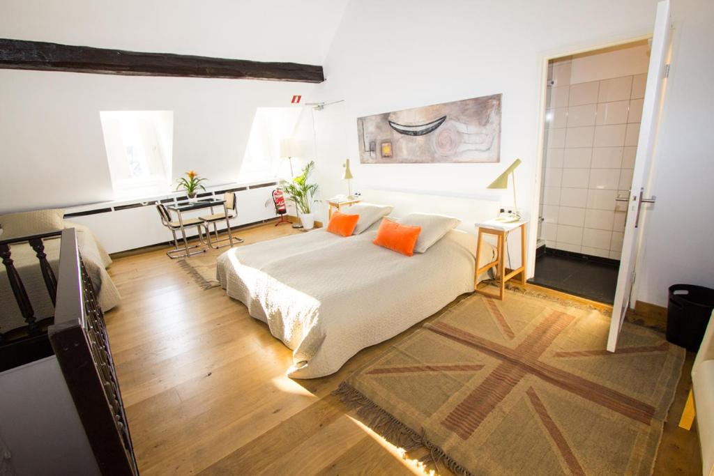 a bedroom with a bed with orange pillows and a table at Galerie Hotel Dis in Maastricht