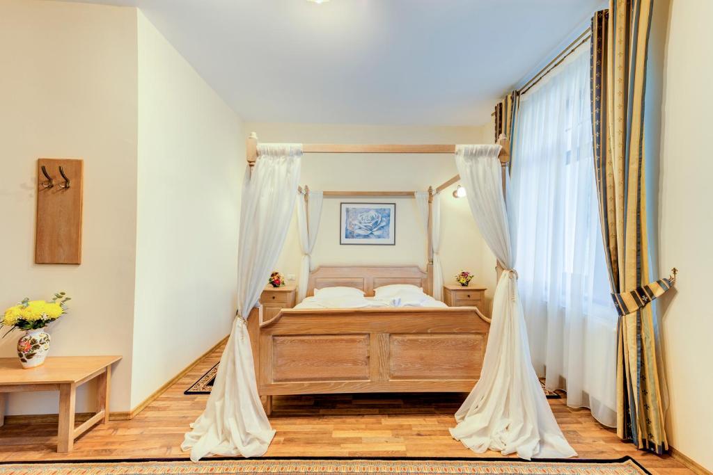 a bedroom with a bed with white curtains at Karlhof in Sebeş