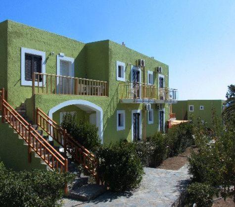 a large green building with a balcony on it at Perla Apartments in Agia Pelagia