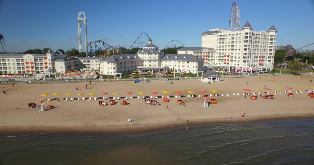 eine Gruppe von Menschen am Strand mit Sonnenschirmen in der Unterkunft Cedar Point Hotel Breakers in Sandusky