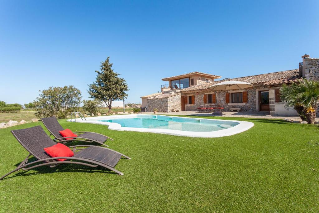 two lawn chairs and a swimming pool in a yard at Finca Can Mel in Búger