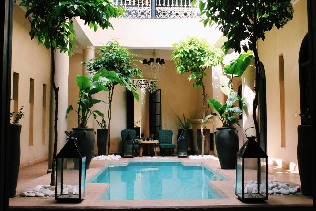 a swimming pool in a courtyard with potted plants at Riad O in Marrakesh