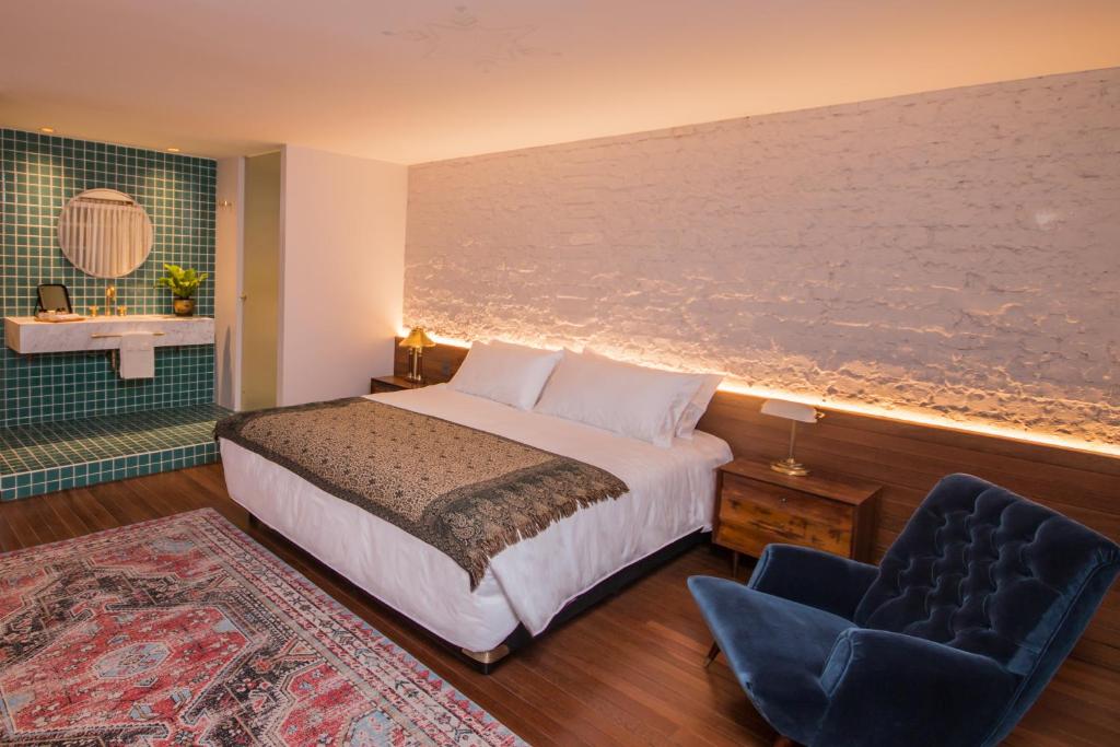 ein Schlafzimmer mit einem Bett und einem blauen Stuhl in der Unterkunft Casa Lelyte in Bogotá