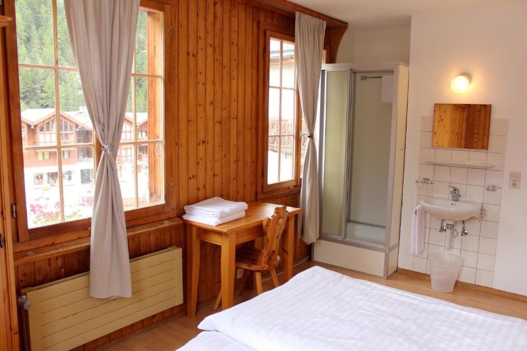 Schlafzimmer mit einem Bett, einem Waschbecken und einem Schreibtisch in der Unterkunft Hôtel - Restaurant Le Trift in Zinal