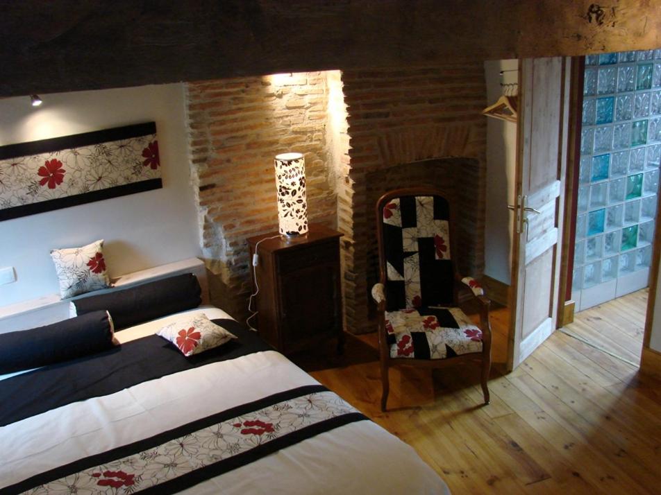 1 dormitorio con cama y pared de ladrillo en L'Ancien Presbytère, en Luzy
