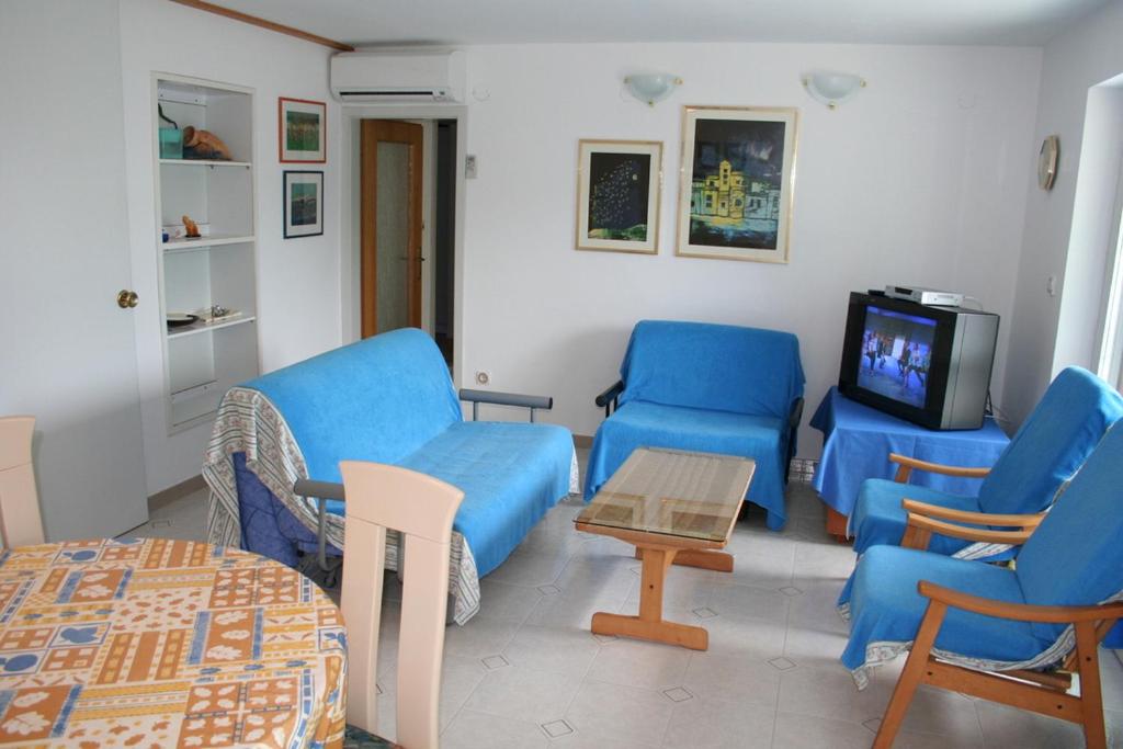 salon z niebieskimi krzesłami i telewizorem w obiekcie Apartments Lada 1217 w mieście Premantura