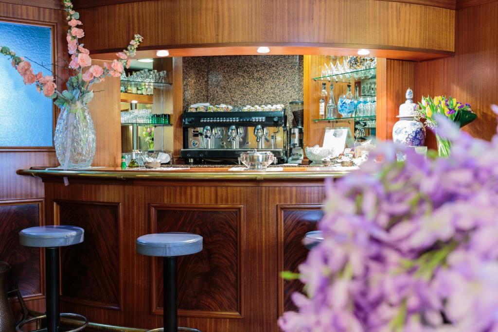 un bar con dos taburetes y un jarrón de flores en Hotel Il Telegrafo, en Melegnano