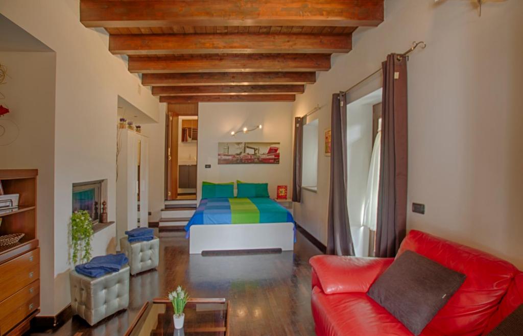 a living room with a bed and a red couch at Casale Pratoterra in Bracciano