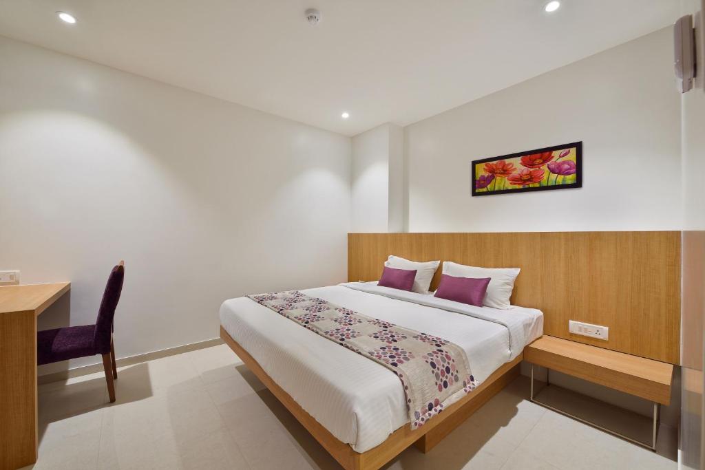 Hotel Leafio-Near Airport في مومباي: غرفة نوم مع سرير ومكتب وسرير sidx sidx
