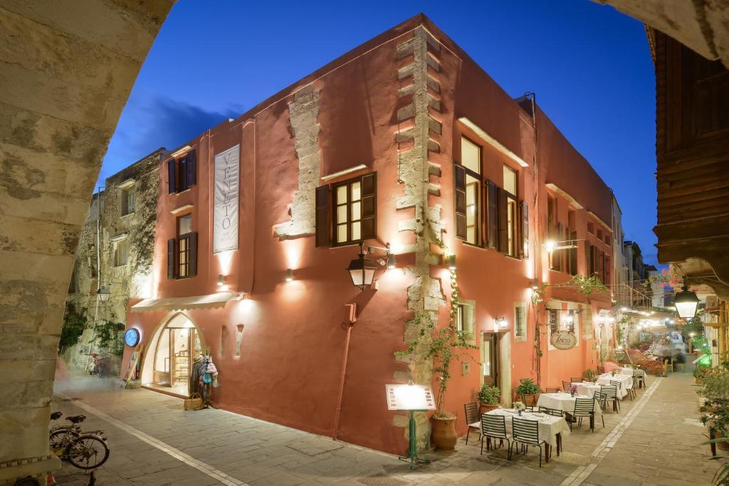 a red building with tables and chairs on a street at Veneto Boutique Hotel in Rethymno
