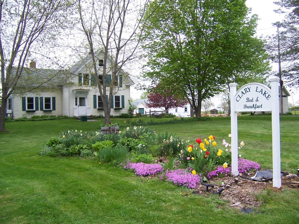 ein Schild in einem Garten mit Blumen vor einem Haus in der Unterkunft Clary Lake Bed and Breakfast in Jefferson