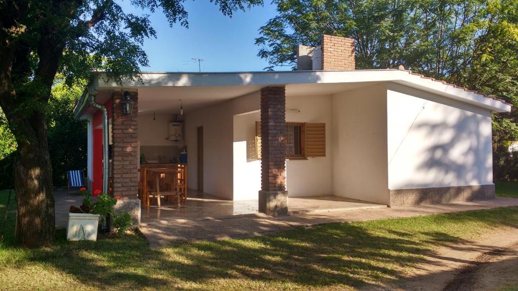 uma pequena casa branca num quintal com uma árvore em Complejo Leon em Villa Rumipal