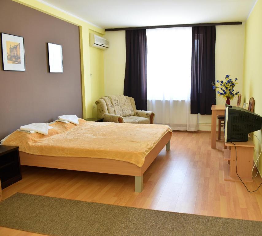 sypialnia z łóżkiem, krzesłem i telewizorem w obiekcie Hostel Milkaza w Nowym Sadzie