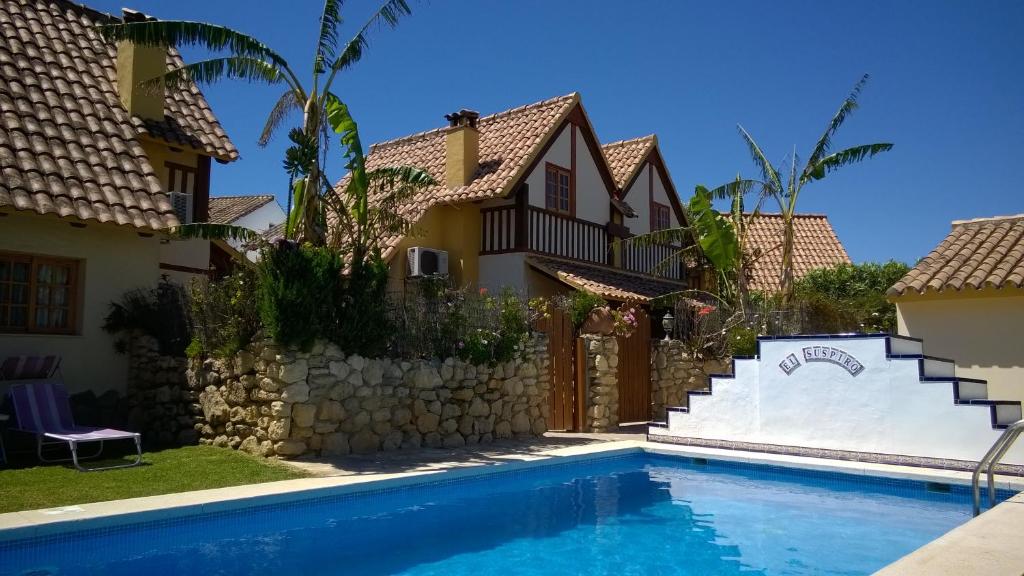 a villa with a swimming pool in front of a house at Casas El Suspiro in Zahora