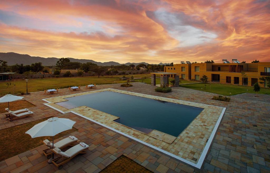 a swimming pool with two chairs and an umbrella at Dera Masuda Luxury Resort in Pushkar