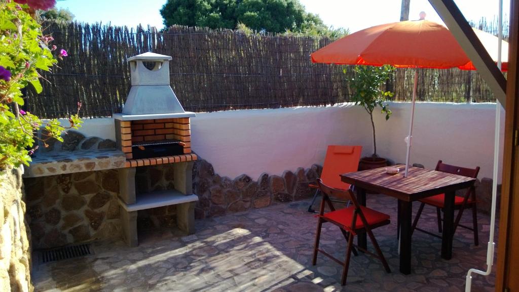a patio with a fireplace and a table with an umbrella at Casas El Suspiro in Zahora