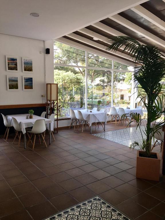 a restaurant with white tables and chairs and a plant at Hotel Marisma Sancti Petri in Chiclana de la Frontera