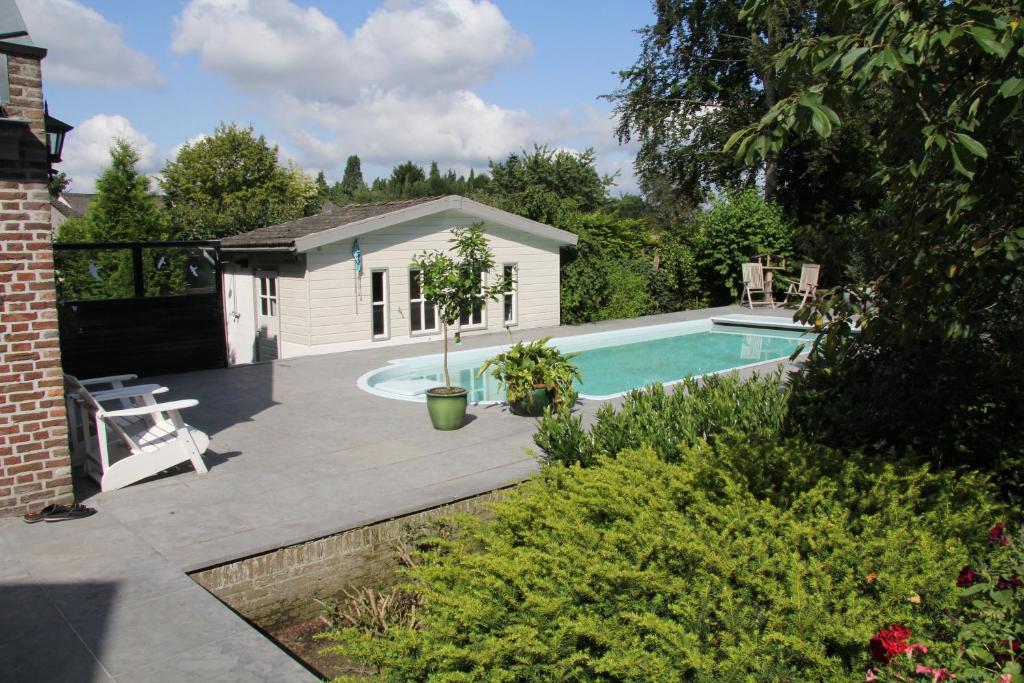 un patio trasero con piscina y una casa en De Oude Pastorie en Netersel