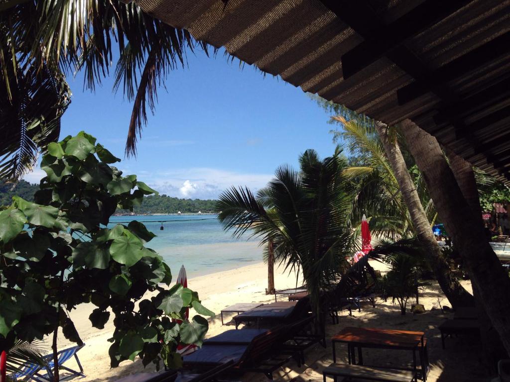 a beach with chairs and palm trees and the ocean at Yuyu Golden Beach in Ko Chang
