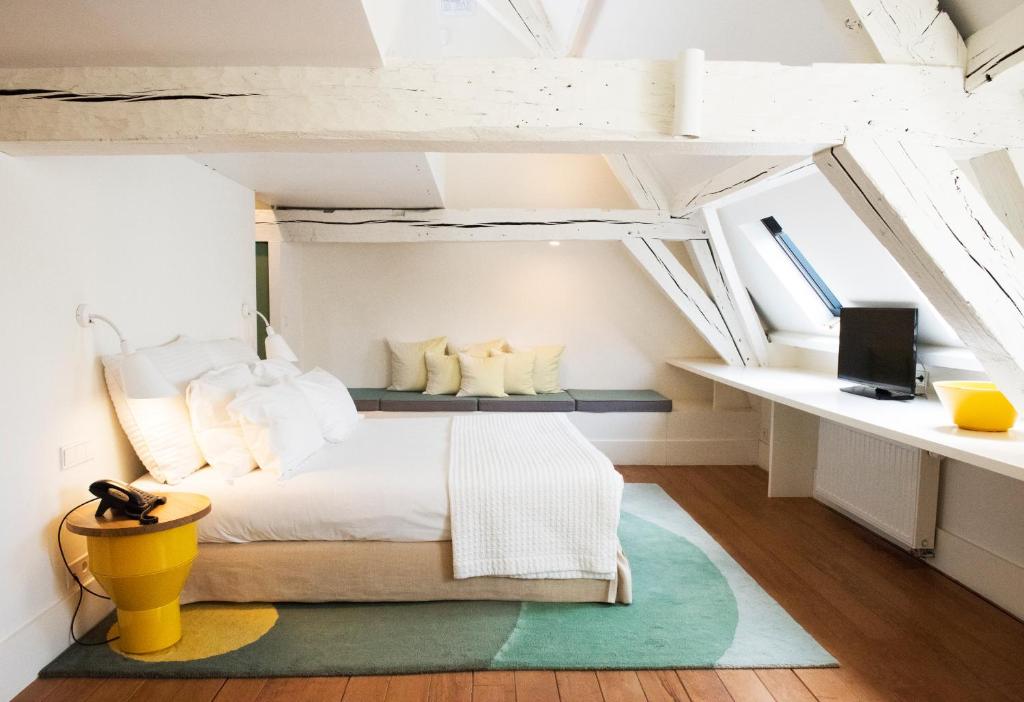 1 dormitorio con cama blanca y taburete amarillo en Hotel des Galeries, en Bruselas