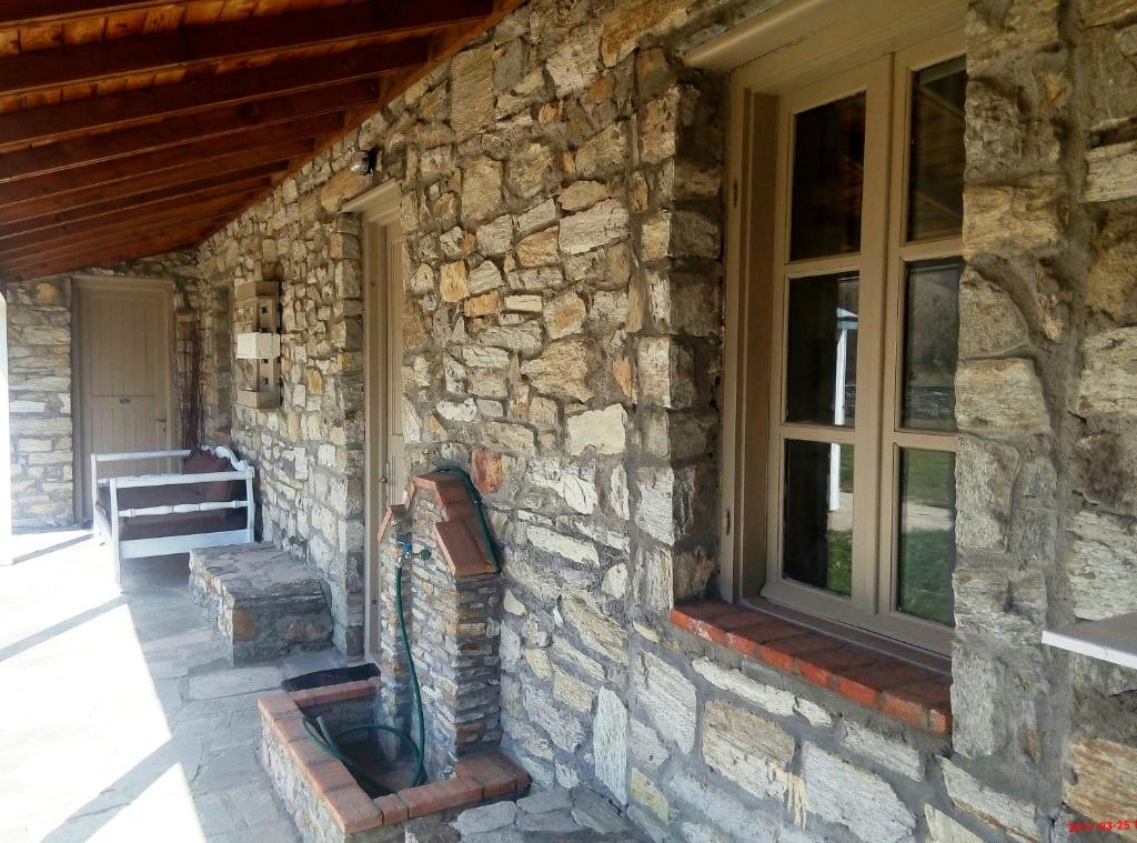 a stone house with a window and a statue on the side at Linouria in Nymfaio