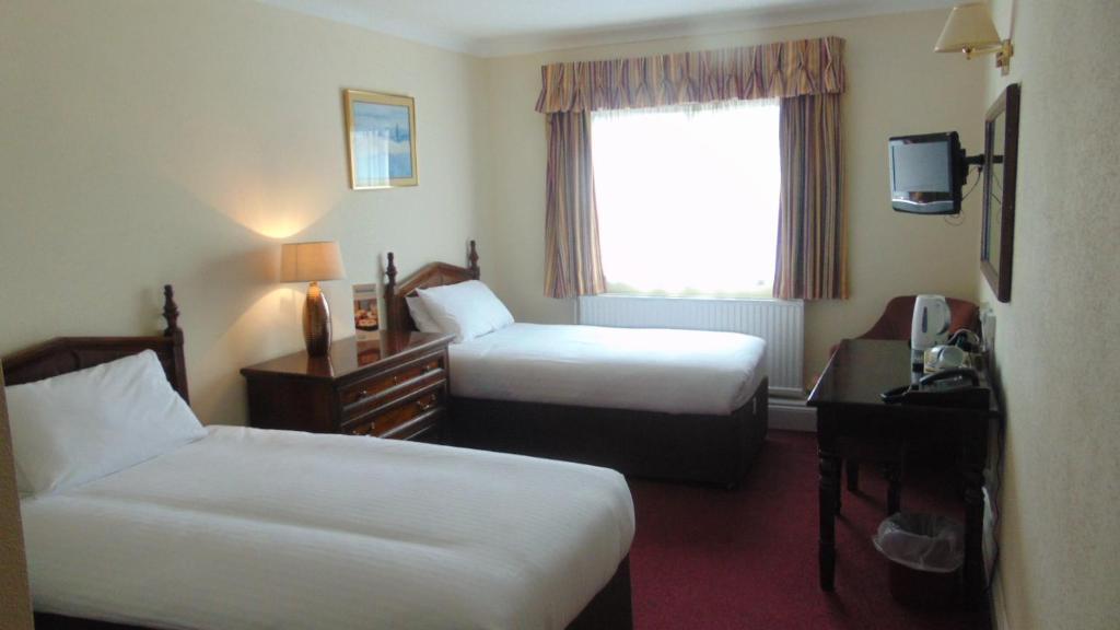 una camera d'albergo con due letti e una finestra di The Harrowgate Hill Lodge a Darlington