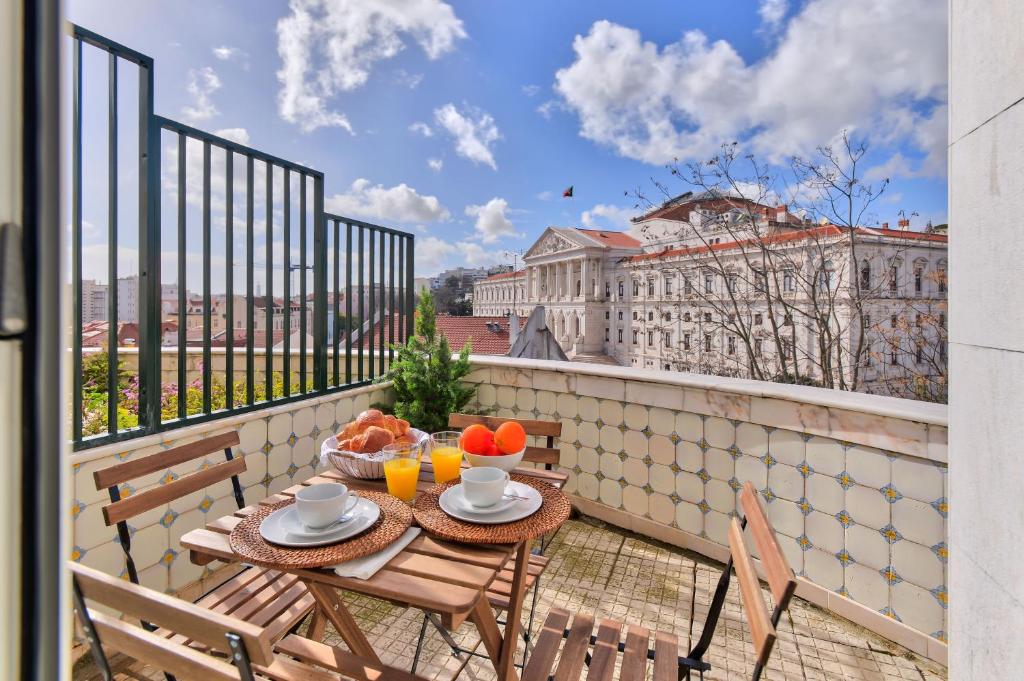 a table and chairs on a balcony with a view of a building at Jardim Das Flores Luxury Apartment in Lisbon