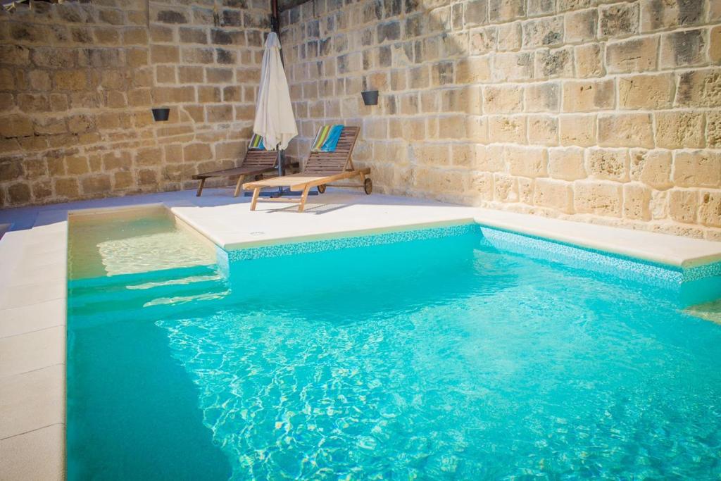 a pool in a room with two chairs and a table at Lemon Tree Relais by CX Collection in Żabbar